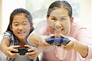 Senior Asian woman and girl playing video game
