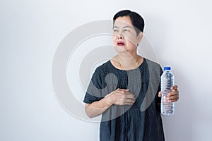 Senior asian woman having or symptomatic reflux acids,Gastroesophageal reflux disease,Drinking water