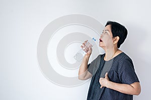 Senior asian woman having or symptomatic reflux acids,Gastroesophageal reflux disease,Drinking water,Copy space on white backgroun