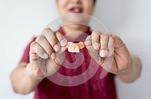 Senior asian woman is holding dentures in hands,Dental prosthesis,False teeth,Close up