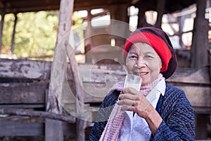 Senior asian woman holding a glass of milk at home in countryside of Thailand