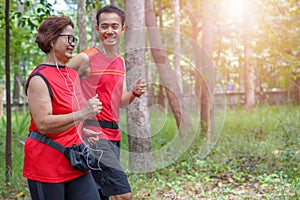 Senior asian woman with man or personal trainer jogging running in the park