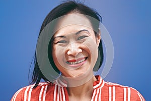 Senior Asian woman portrait against blue background - Smiling Chinese female having fun posing in front of camera