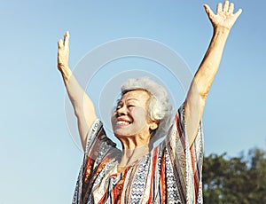 Senior Asian woman raising her arms