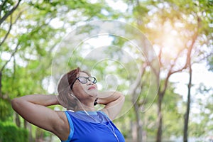 Senior asian woman relaxed listening to music in the park, Exercise sport activity concept