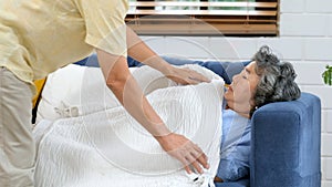 Senior asian woman sleeping on sofa and her husband covering blanket, Asian man elderly comfort and take care while senior woman
