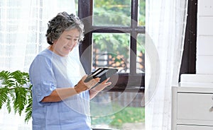 Senior asian woman using digital tablet computer at home background, Retirement asian woman and digital tablet standing by home