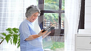 Senior asian woman using digital tablet computer at home background, Retirement asian woman and digital tablet standing by home