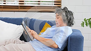 Senior asian woman using digital tablet computer, Retirement asian woman and digital tablet while lying on sofa at home living