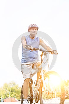 Senior athlete riding bicycle against sky