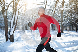 Senior athletic man in sportswear running at winter park, copy space. Seasonal outdoor sports and cold tempering concept