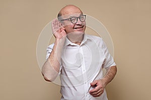 Senior bald male adult in glasses listening carefully, spying, being curious