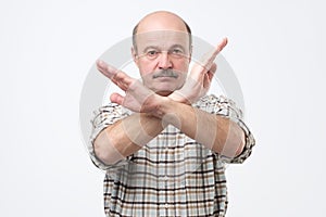 Senior bald man with mustache making stop sign with hand. I do not give you a permission.