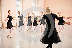 Senior ballet instructor demonstrating moves in front of a group of teenage girls