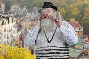 Senior bearded man in hat talking on the mobile phone.