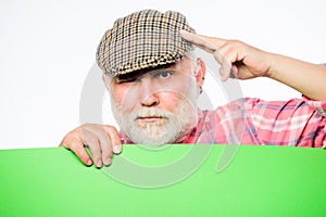 Senior bearded man peek out of banner place announcement. Pensioner grandfather in vintage hat hold poster information