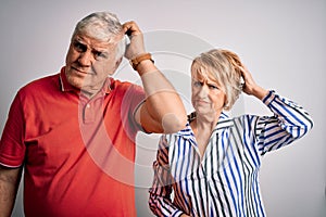 Senior beautiful couple standing together over isolated white background confuse and wondering about question