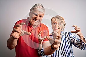 Senior beautiful couple standing together over isolated white background Shouting frustrated with rage, hands trying to strangle,