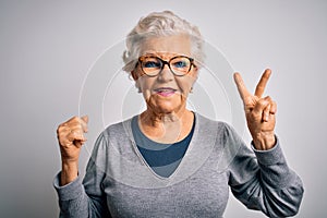 Senior beautiful grey-haired woman wearing casual sweater and glasses over white background smiling with happy face winking at the