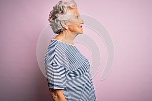 Senior beautiful grey-haired woman wearing casual t-shirt over isolated pink background looking to side, relax profile pose with
