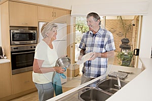 Senior beautiful middle age couple around 70 years old smiling happy at home kitchen washing the dishes looking sweet together