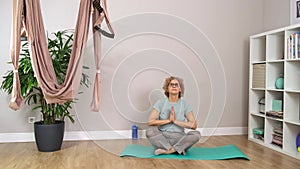 Senior beautiful sporty woman wearing glasses is meditating