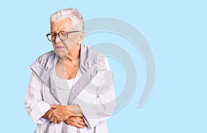 Senior beautiful woman with blue eyes and grey hair wearing casual clothes and glasses with hand on stomach because nausea,