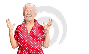 Senior beautiful woman with blue eyes and grey hair wearing a red summer dress celebrating mad and crazy for success with arms