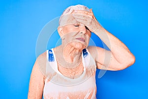 Senior beautiful woman with blue eyes and grey hair wearing sporty sleeveless shirt surprised with hand on head for mistake,