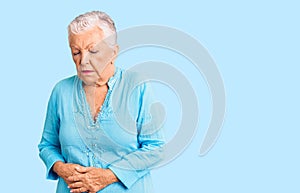 Senior beautiful woman with blue eyes and grey hair wearing summer dress with hand on stomach because indigestion, painful illness