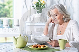 senior beautiful woman reading newspaper at home