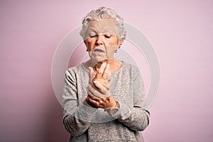 Senior beautiful woman wearing casual t-shirt standing over isolated pink background Suffering pain on hands and fingers,