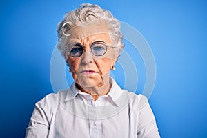 Senior beautiful woman wearing elegant shirt and glasses over isolated blue background skeptic and nervous, disapproving