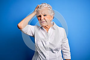 Senior beautiful woman wearing elegant shirt standing over isolated blue background confuse and wonder about question