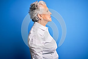 Senior beautiful woman wearing elegant shirt standing over isolated blue background looking to side, relax profile pose with