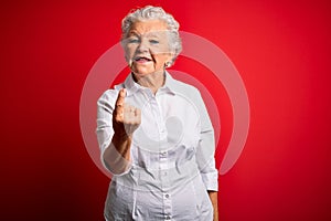 Senior beautiful woman wearing elegant shirt standing over isolated red background Beckoning come here gesture with hand inviting