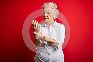 Senior beautiful woman wearing elegant shirt standing over isolated red background Suffering pain on hands and fingers, arthritis