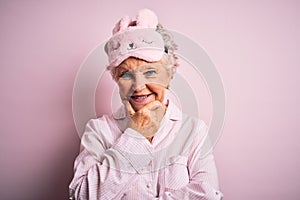 Senior beautiful woman wearing sleep mask and pajama over isolated pink background looking confident at the camera smiling with