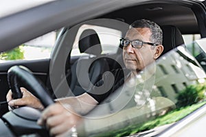 Senior behind the steering wheel looking at map for directions