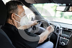 Senior behind the steering wheel looking at map for directions