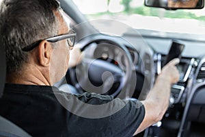 Senior behind the steering wheel looking at map for directions