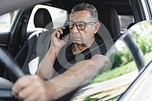 Senior behind the steering wheel looking at map for directions