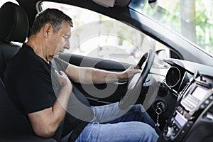 Senior behind the steering wheel looking at map for directions