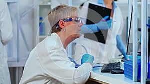 Senior biochemist typing and looking on pc analysing medical reports