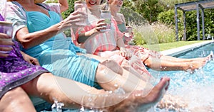 Senior biracial woman and Caucasian woman enjoy a sunny day by the pool