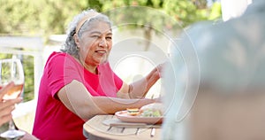 Senior biracial woman enjoys a meal outdoors, with copy space