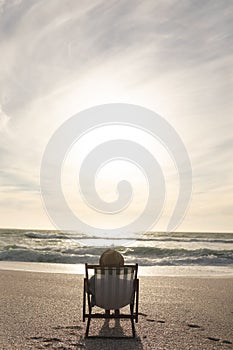 Senior biracial woman sitting on folding chair relaxing at beach in front of horizon over sea
