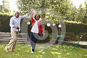 Senior black couple dance in their back garden, full length