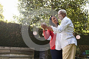 Senior black couple dancing in their back garden