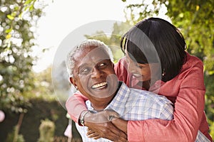 Senior black couple piggyback, looking at each other